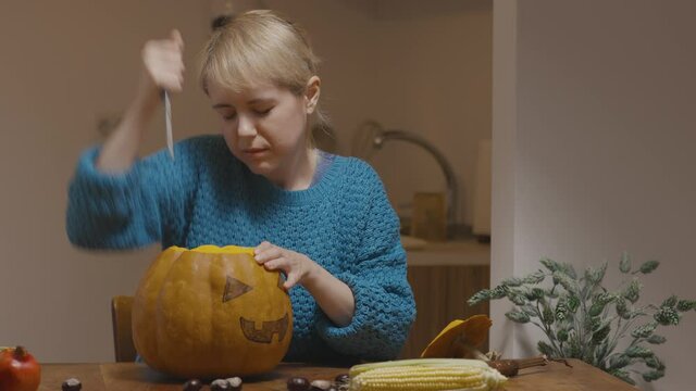 Young woman carving face on pumpkin for halloween
