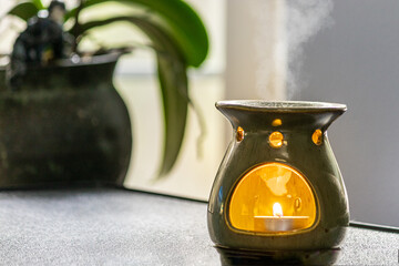 essential oil burner near orchid on table