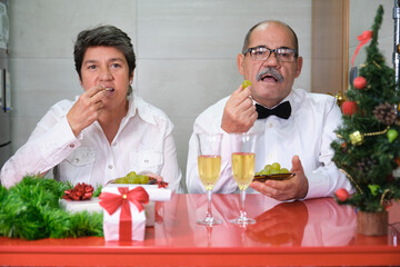 Senior couple celebrating new year eating grapes. Spanish new year tradition. Christmas celebration concept.