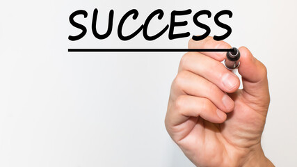 the hand writes the Word SUCCESS with a marker on a white background. business concept