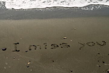 Words I Miss You written on sea beach