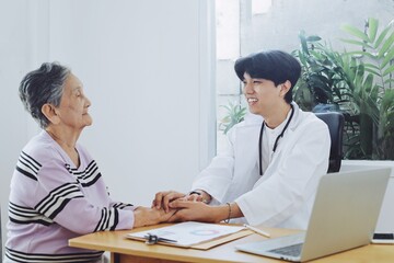 Young doctor examining elderly woman in hospital.