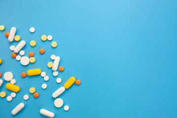 Scattered pills on blue photo. Pharmaceuticals concept