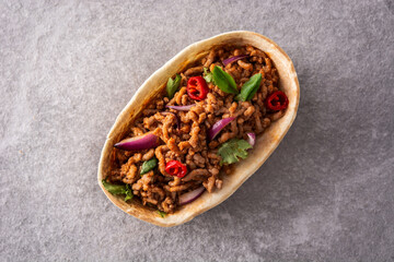 Mexican barquita taco with beef, chilli, tomato, onion and spices on gray stone	