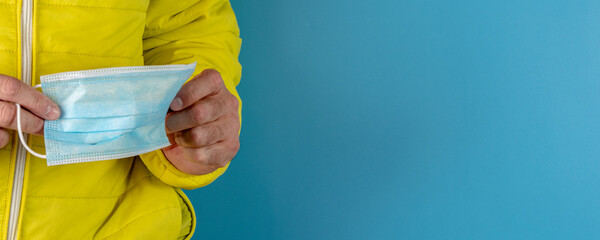 man in yellow jacket is using a protective mask against corona virus on blue background