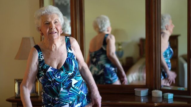 Elderly woman models a bathing suit she uses in water aerobics classes. Concept of active senior female having fun in retirement.