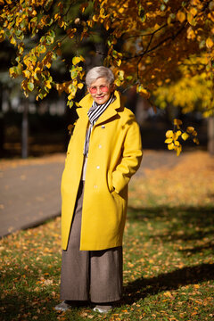 adult woman in yellow coat in the park in autumn