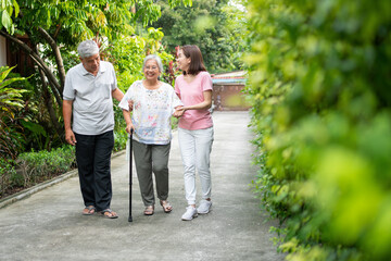 Happy family walking together in the garden. Old elderly using a walking stick to help walk...