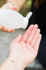 Girl sharing hand sanitiser at a park