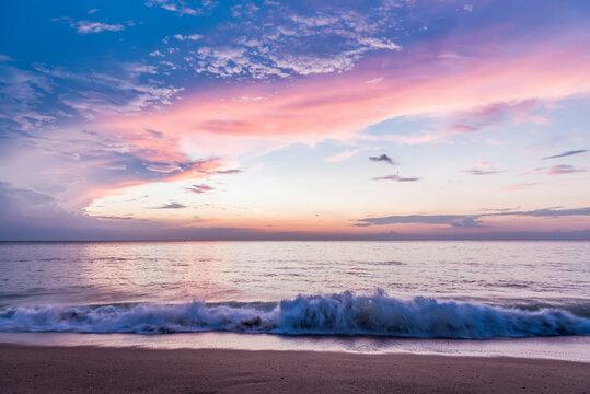 A colorful sunset over the Andaman sea and the waves coming to the beach