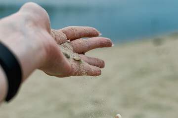 River shells and fine white river sand fall from a woman's hand in nature
