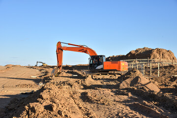 Excavator Working On Road Construction. Backhoe on Earthworks. Heavy Construction Equipment. for road works. Digger at construction site. Soft focus, possible granularity