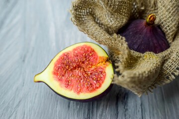 Bright purple luscious figs wrap in fabric on a gray wooden background. 