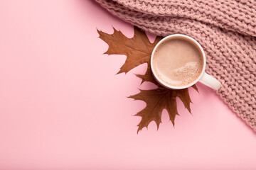 Autumn cozy composition. Dry brown leaves, hot chocolate, pink knitted sweater.