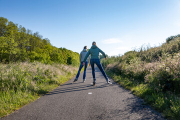 2 girls skate on a cycle path along the A44 motorway in the South Holland village of Sassenheim in the Netherlands.