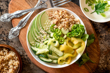 Burrito bowl with quinoa and green vegetables. Salad of quinoa, cucumber, peppers, radishes and celery in a bowl close-up. Top view, selective focus. Healthy diet food, vegetarian food.