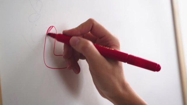 Female hand writes the word LOVE with a marker on a white board