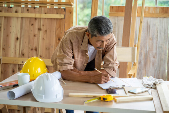 senior Asian man working on wood  work home improvement DIY in workshop recoding streaming online