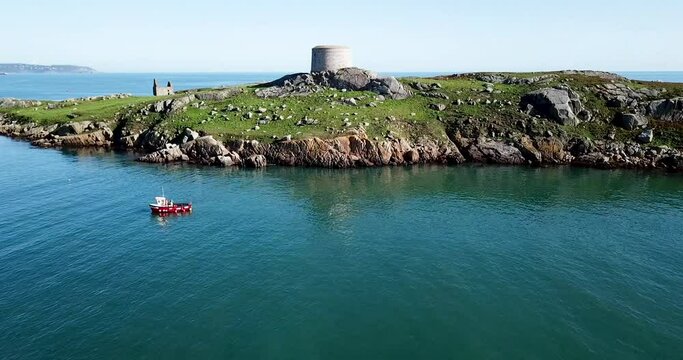 Aerial footage of little red fishing boat catching fish near Dalkey Island and Coliemore harbour on sunny day.