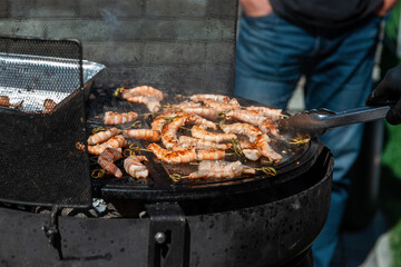 A professional cook prepares shrimps on the grill outdoor, food or catering concept
