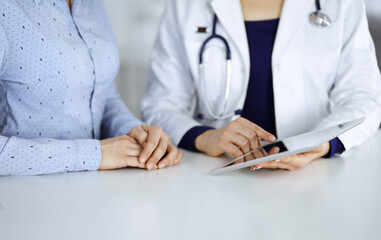Unknown woman-doctor is showing to her patient a description of medication, while sitting together...