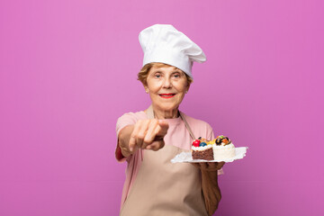 mature beautiful old woman pointing at camera with a satisfied, confident, friendly smile, choosing you