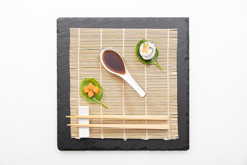 Présentation de plat de cuisine Japonaise, dés de saumon, sushi et maki sur fond noir avec sauce soja.	