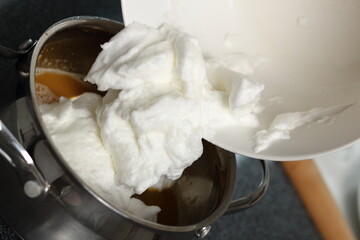 Fototapeta na wymiar Transfer whisked egg whites into pan with filling mixture. Making Cider Pie Series.