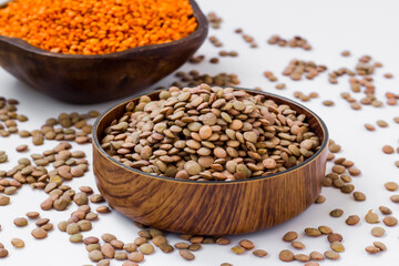 Dry,Red and Green Lentils are in wooden bowls on white surface with lentil seeds.