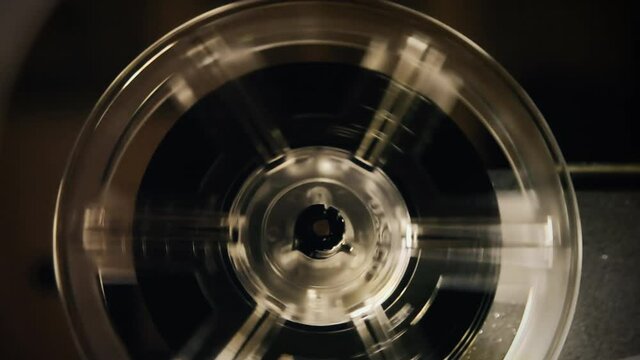 The running reel of a vintage Super 8 mm film projector, surrounded by a mystic light from the lens. Detail shot.
