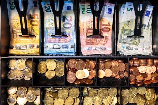 Open money drawer of a register in a European small business. Top view of bills organized into slots of a cash tray, with banknotes of 50, 20, 10 and 5 Euros, and coins of all Euro Zone denominations
