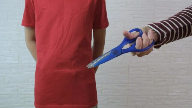 A person clicking the scissors in front of a boy, traditional circumcision procedure concept