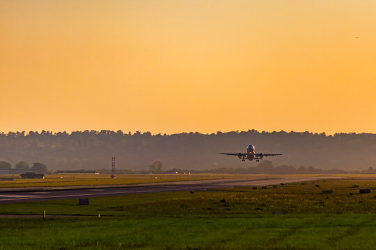 Passenger aircraft short after take off in evening lights. Airplane above airport runway at sunset. Dark, soft, dreamy colors