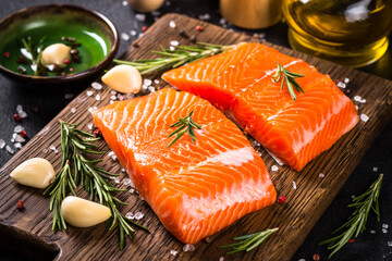 Salmon fish with ingredients at black table.