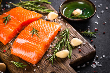 Salmon fish with ingredients at black table.