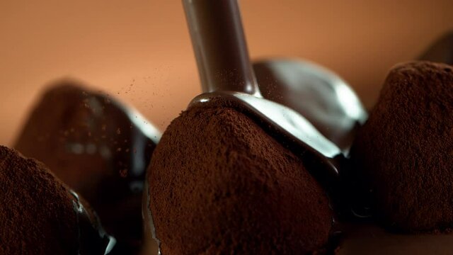 Super slow motion of pouring dark hot chocolate on praline bonbon. Filmed with cinema high speed camera