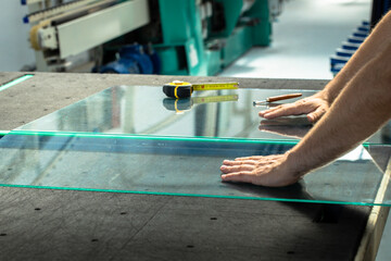 Glazier cuts and breaks glass on a professional table in the workplace - obrazy, fototapety, plakaty