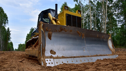 Dozer during clearing forest for construction new road . Yellow Bulldozer at forestry work Earth-moving equipment at road work, land clearing, grading, pool excavation, utility trenching © MaxSafaniuk