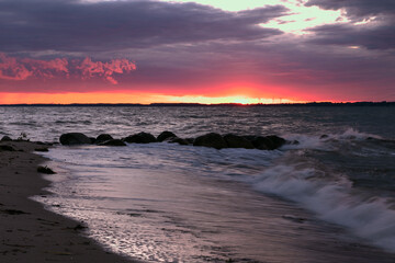 dramatischer Himmel mit Wellenl am Meer bei Sonnenuntergang