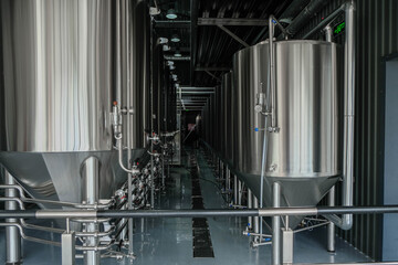 Naklejka premium Lines of metal tanks in a modern craft brewery. Fermentation. 
