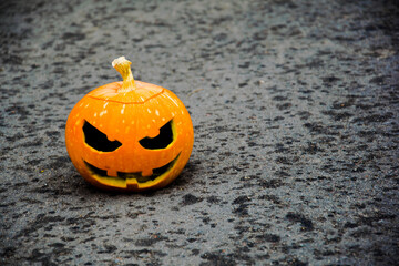 Halloween pumpkin in left corner on tarmac road with blurred background