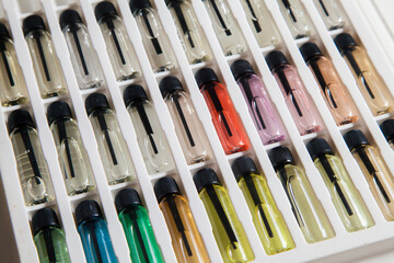 Sample of colored perfume bottles with different types of fragrances and aromas in a makeup case on the table. Beauty concept. Feminine concept. Colorful concept.