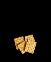 Soda crackers with salt on black background, snack concept