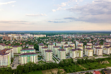 Fototapeta na wymiar Top view of urban developing city landscape with tall apartment buildings and suburb houses. Drone aerial photography.