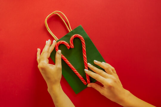 Two Red Candy Striped Canes Lie On A Green Packet On A Red Background