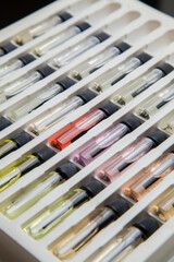 Sample of colored perfume bottles with different types of fragrances and aromas in a makeup case on the table. Beauty concept. Feminine concept. Colorful concept.