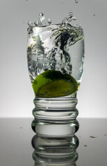 Lime splashing water from glass.