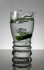 Lime splashing water from glass.
