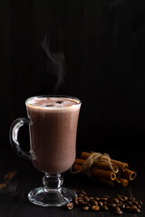 glass of cappuccino with whipped cream on a dark table. cup of coffee and chocolate with cinnamon sticks. hot chocolate on a wooden background. hot drinks winter and autumn. vertical. copy space.