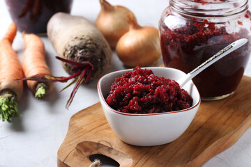 Homemade caviar from beets and carrots in bowl and jar on wooden board and fresh ingredients on a light gray background